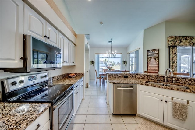 3914 SW 17th Ave, Cape Coral, FL 33914 - kitchen with stainless steel appliances, dark stone countertops, a chandelier, light tile patterned flooring, and a sink