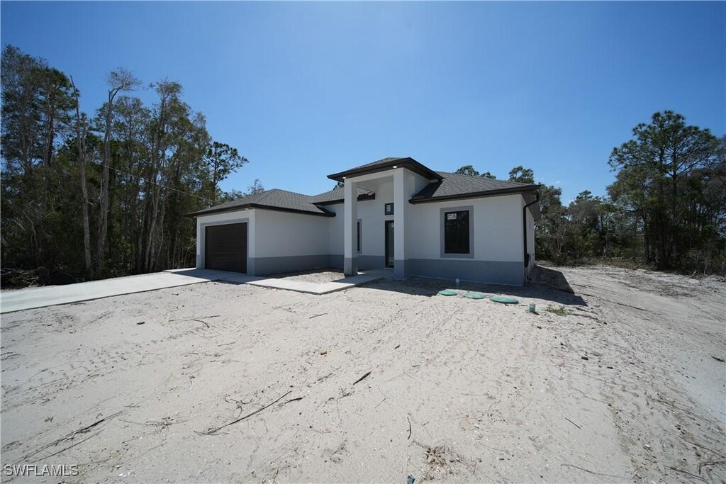 712 Goldwyn Ave S, Lehigh Acres, FL 33974 - prairie-style house featuring an attached garage and stucco siding