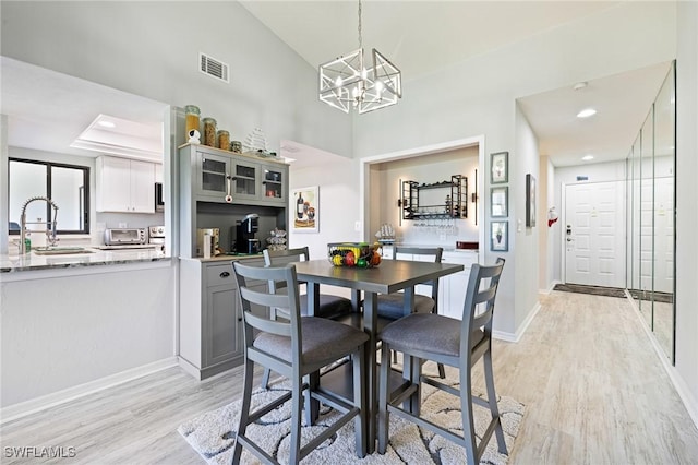 dining area featuring a notable chandelier, light wood finished floors, baseboards, a toaster, and visible vents