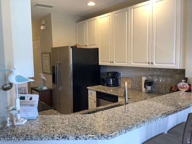 11735 Eros Rd, Lehigh Acres, FL 33971 - kitchen featuring white cabinets, light stone countertops, refrigerator with ice dispenser, and visible vents
