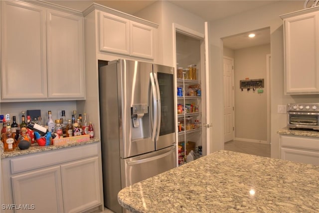 1410 SW 38th St, Cape Coral, FL 33914 - kitchen with stainless steel fridge, white cabinets, light stone counters, and recessed lighting