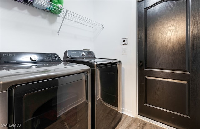 washroom featuring separate washer and dryer, laundry area, and wood finished floors