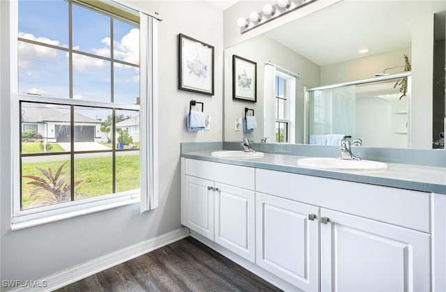 full bath featuring baseboards, a shower stall, a sink, and wood finished floors