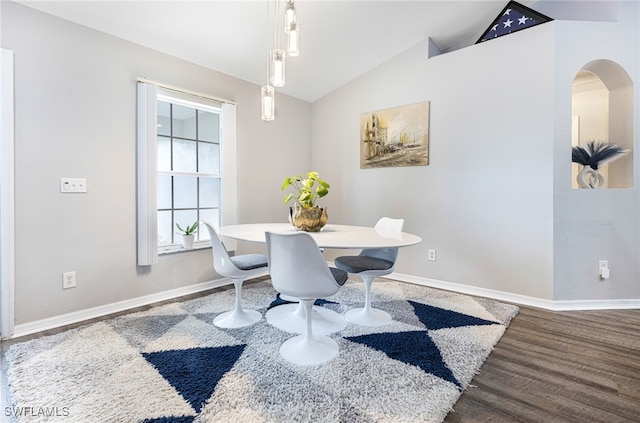 dining room with baseboards, vaulted ceiling, arched walkways, and wood finished floors