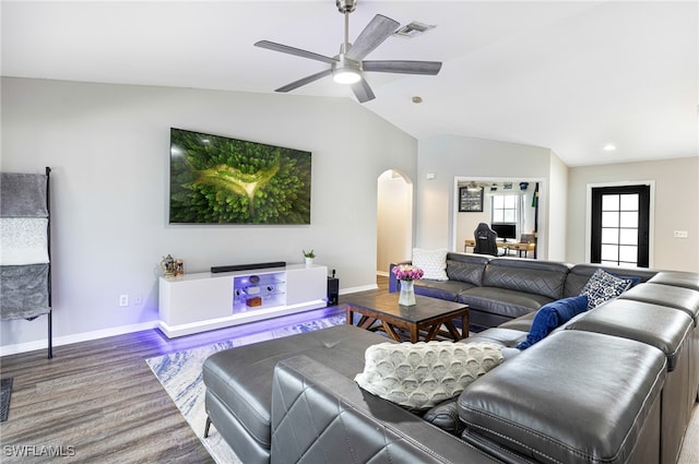 living area with a ceiling fan, visible vents, arched walkways, vaulted ceiling, and baseboards