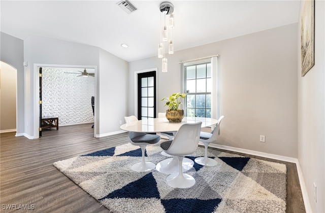 dining area featuring visible vents, arched walkways, baseboards, and wood finished floors