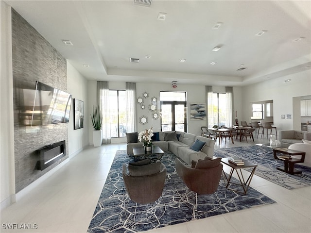 living area featuring a wealth of natural light, a raised ceiling, and visible vents