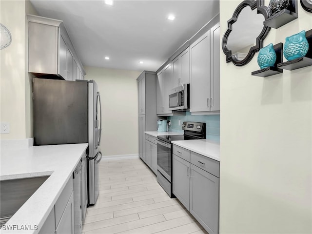kitchen featuring decorative backsplash, gray cabinetry, stainless steel appliances, baseboards, and recessed lighting