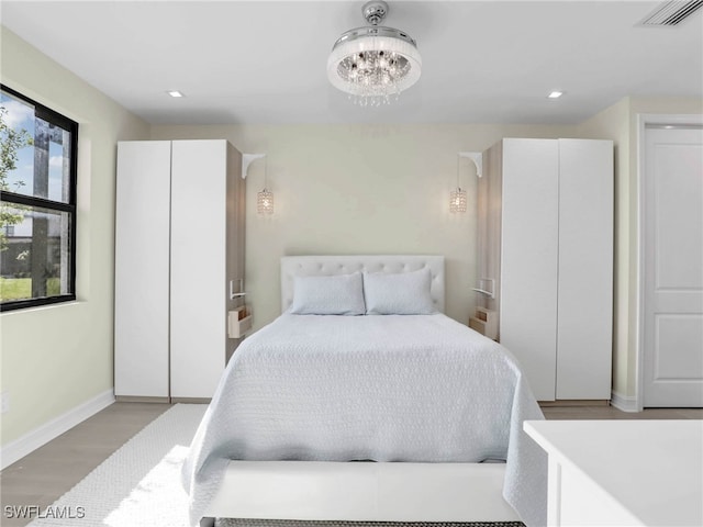 bedroom featuring recessed lighting, an inviting chandelier, visible vents, baseboards, and wood finished floors