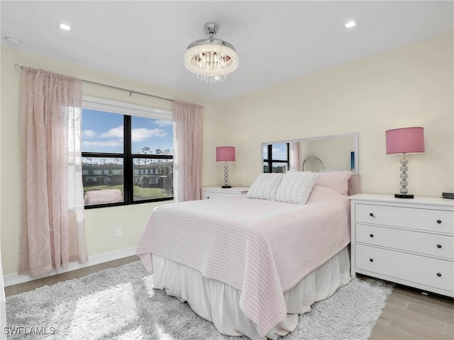 bedroom with baseboards, a chandelier, and light wood-style floors