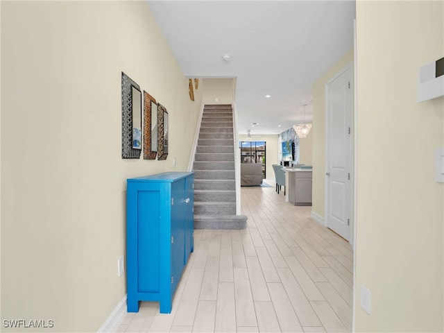 hall featuring baseboards, light wood finished floors, and stairs