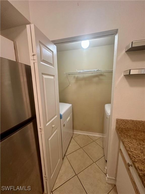 laundry room with baseboards, laundry area, separate washer and dryer, and light tile patterned floors