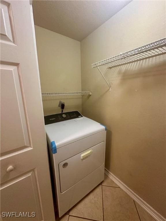 clothes washing area featuring baseboards, washer / clothes dryer, laundry area, and light tile patterned floors