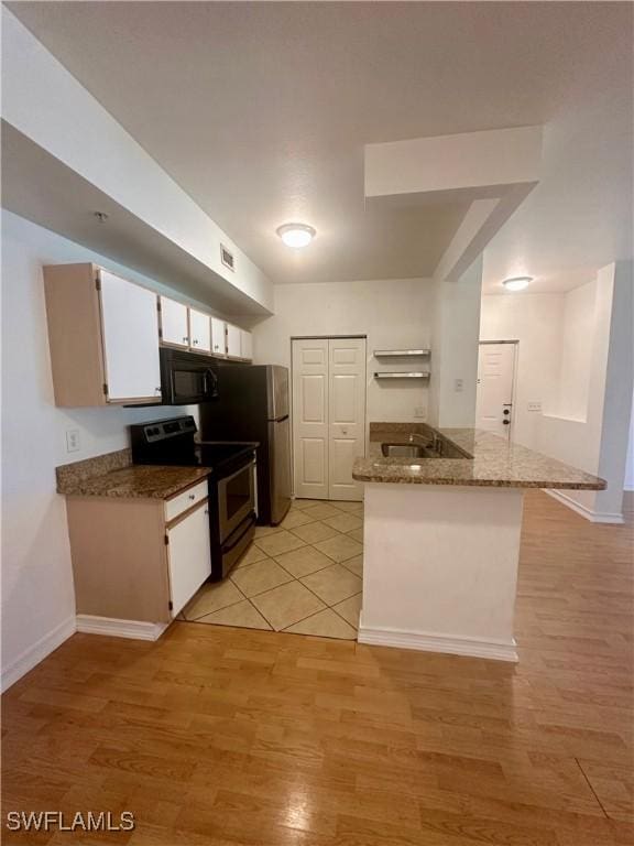 kitchen with black microwave, electric stove, visible vents, white cabinets, and light wood-style floors