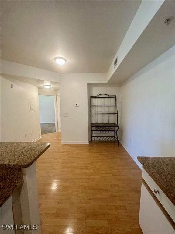 unfurnished dining area featuring baseboards, visible vents, and light wood-style floors