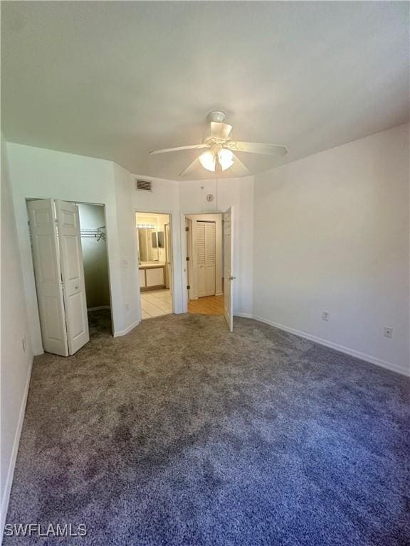 unfurnished bedroom with visible vents, baseboards, connected bathroom, ceiling fan, and carpet floors