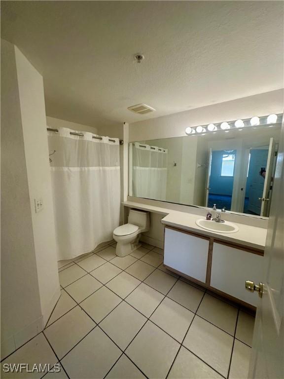 full bath with a shower with curtain, tile patterned flooring, vanity, toilet, and a textured ceiling