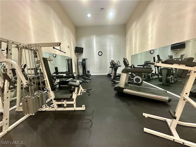 gym featuring baseboards, a towering ceiling, and visible vents