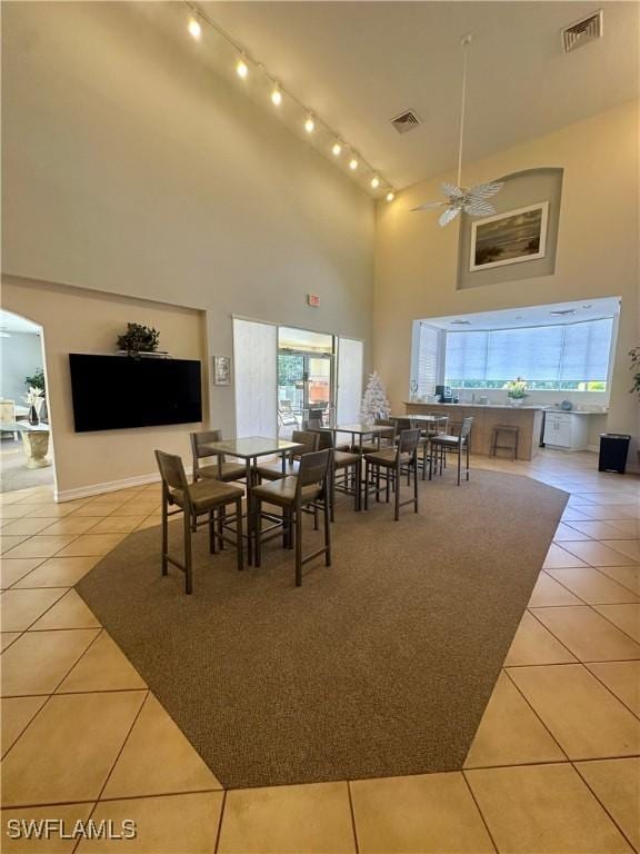 dining room with light tile patterned floors, high vaulted ceiling, and visible vents