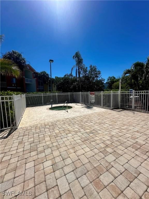 view of patio with a community hot tub and fence