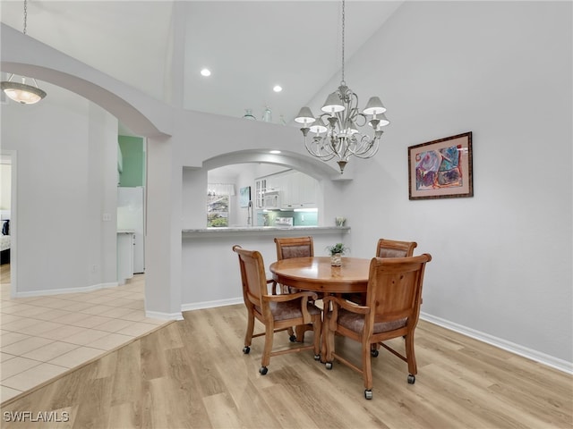 5774 Greenwood Cir Unit 64, Naples, FL 34112 - dining space featuring an inviting chandelier, high vaulted ceiling, arched walkways, and light wood-style floors