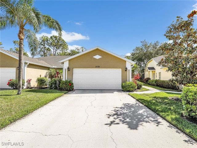 5774 Greenwood Cir Unit 64, Naples, FL 34112 - view of front of property featuring a front yard, concrete driveway, stucco siding, and an attached garage