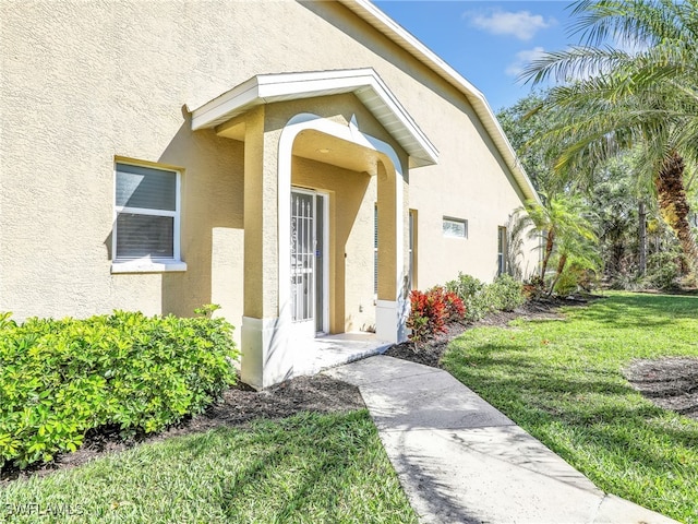 5774 Greenwood Cir Unit 64, Naples, FL 34112 - doorway to property featuring stucco siding and a yard