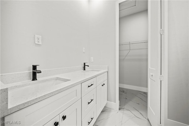full bathroom with baseboards, marble finish floor, a sink, and a spacious closet