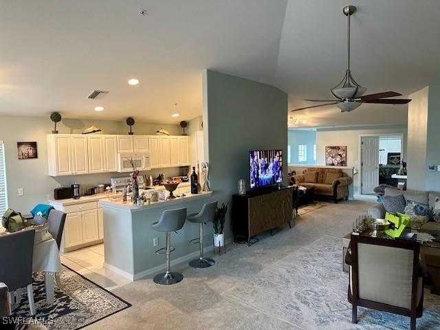 1280 Henley St Unit 1601, Naples, FL 34105 - kitchen featuring a ceiling fan, a kitchen bar, visible vents, white microwave, and open floor plan