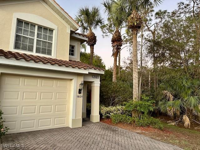 1280 Henley St Unit 1601, Naples, FL 34105 - view of property exterior featuring a garage, decorative driveway, stucco siding, and a tile roof