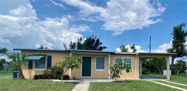 view of front facade with an attached carport, stucco siding, central air condition unit, and a front yard