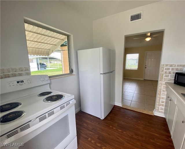 kitchen with light countertops, white cabinetry, white appliances, visible vents, and dark wood-style flooring