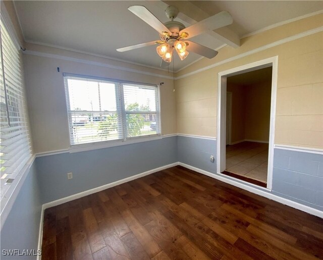 spare room with a ceiling fan, ornamental molding, baseboards, and wood finished floors