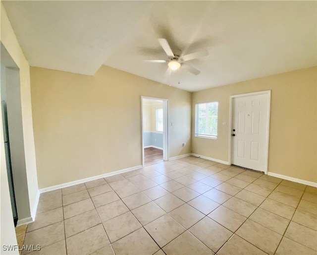 unfurnished room with light tile patterned flooring, baseboards, and a ceiling fan