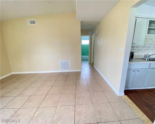 empty room featuring baseboards, visible vents, a sink, and light tile patterned floors