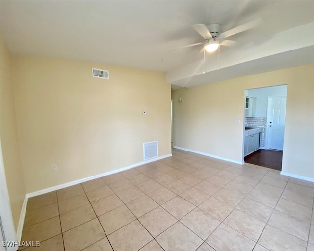 spare room featuring baseboards, visible vents, ceiling fan, and light tile patterned floors