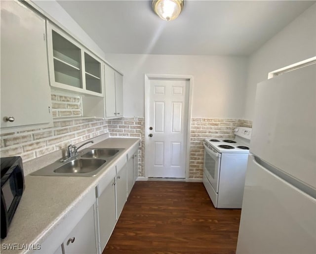 kitchen featuring light countertops, backsplash, a sink, dark wood finished floors, and white appliances
