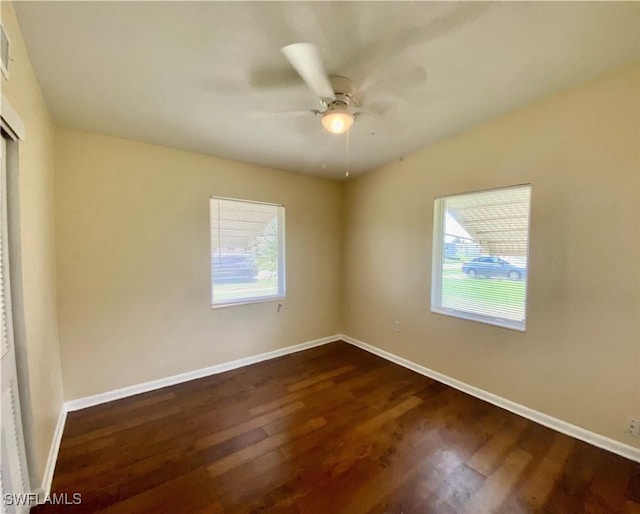 empty room with dark wood-style flooring, baseboards, and ceiling fan