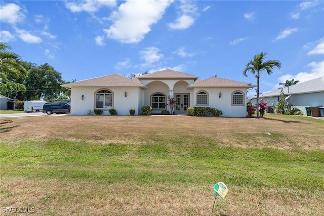 mediterranean / spanish home with french doors, stucco siding, and a front lawn