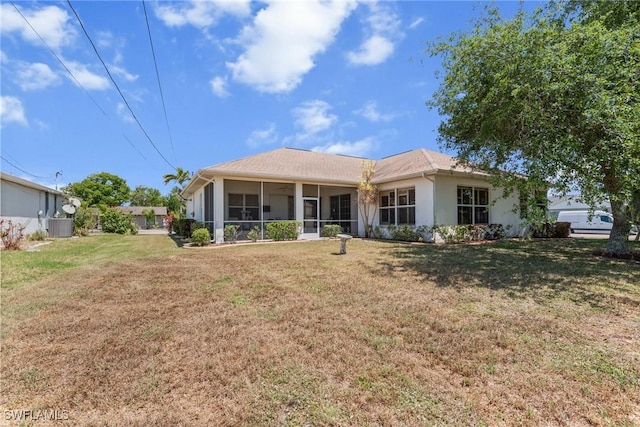 rear view of house with a sunroom, central AC unit, stucco siding, and a yard