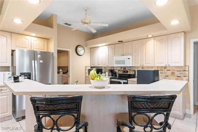 kitchen with appliances with stainless steel finishes, light tile patterned floors, a breakfast bar area, and ceiling fan