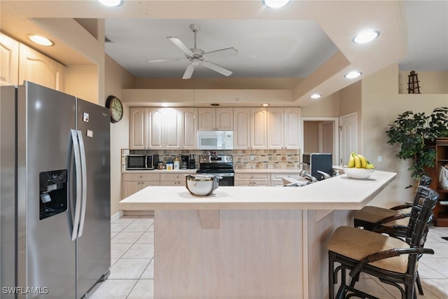 kitchen featuring a breakfast bar area, light countertops, light tile patterned floors, backsplash, and stainless steel appliances