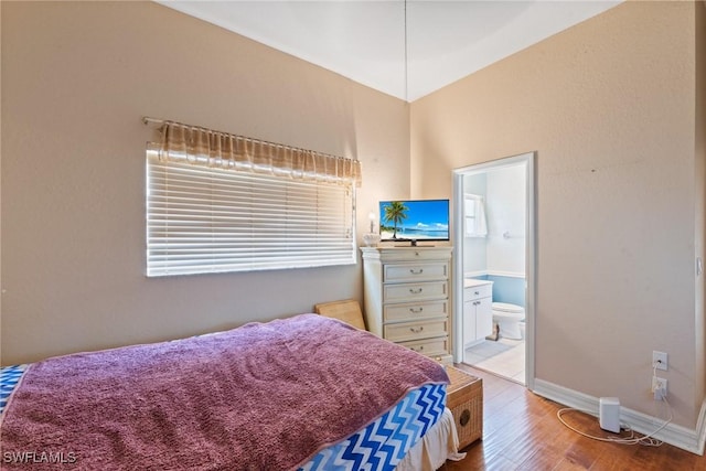 bedroom featuring baseboards, ensuite bathroom, and light wood-type flooring