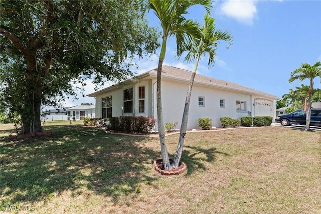 view of side of home with an attached garage, a yard, and stucco siding