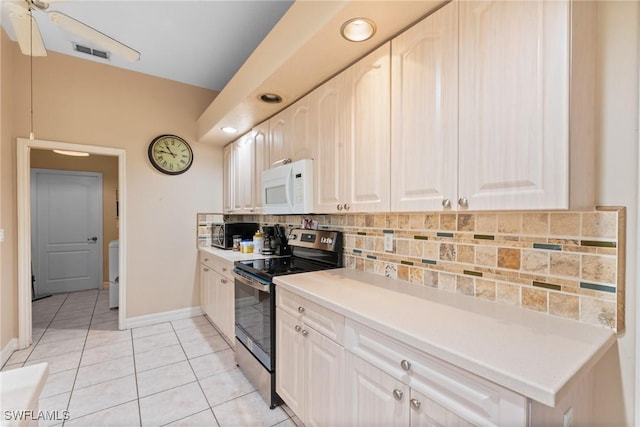 kitchen with stainless steel electric range oven, light tile patterned flooring, white microwave, backsplash, and visible vents