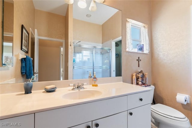 bathroom featuring vanity, a shower stall, and toilet