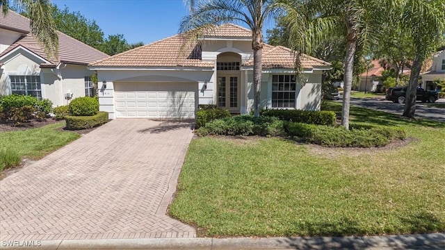 mediterranean / spanish house with a tile roof, stucco siding, an attached garage, decorative driveway, and a front yard