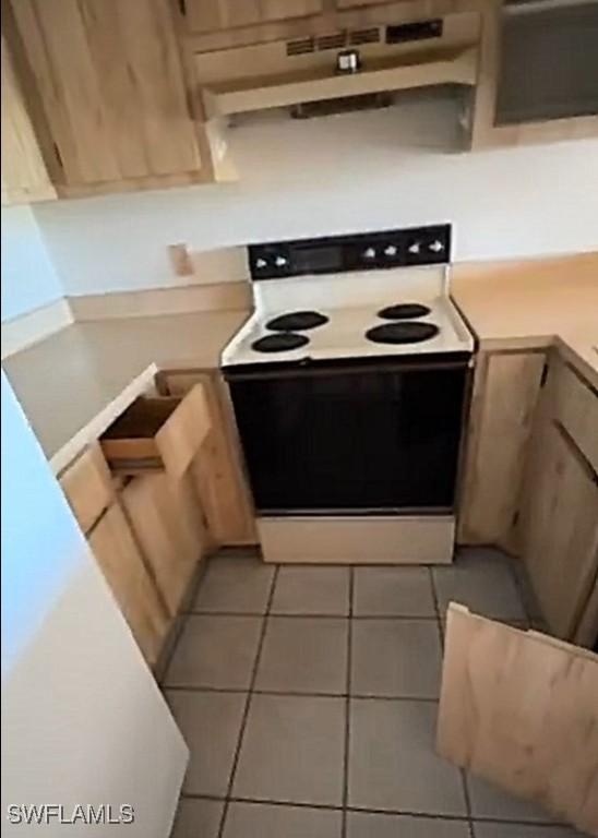 kitchen featuring light countertops, light tile patterned flooring, under cabinet range hood, and range with electric stovetop