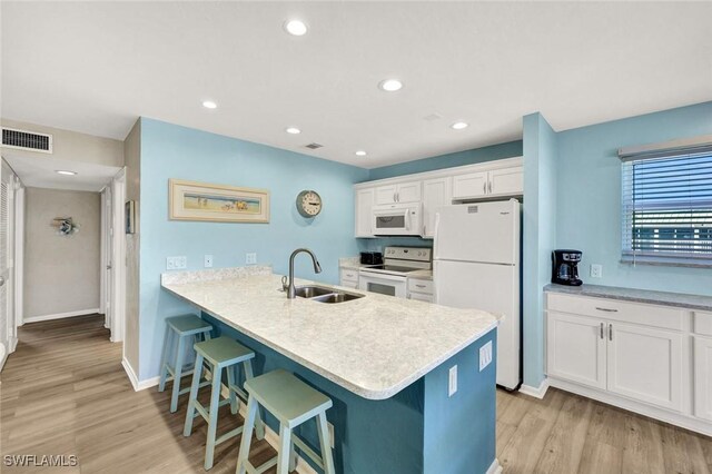 827 E Gulf Dr Unit K8, Sanibel, FL 33957 - kitchen with white cabinets, white appliances, a sink, light wood-style floors, and a kitchen breakfast bar