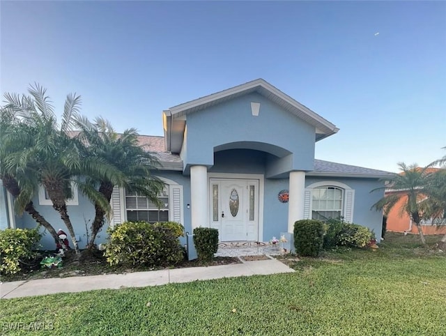 3012 10th St W, Lehigh Acres, FL 33971 - view of front of property with a front lawn, stucco siding, and roof with shingles